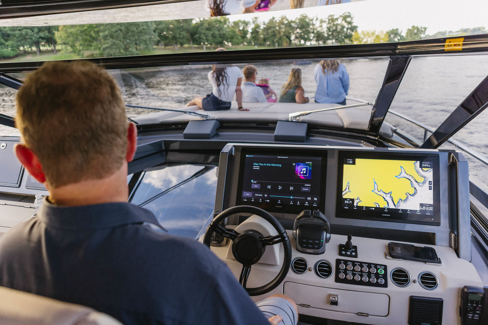 Captain at the helm of an Iconic charter yacht with guests relaxing on the bow